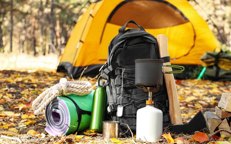 Tourist's survival kit and camping tent in autumn forest