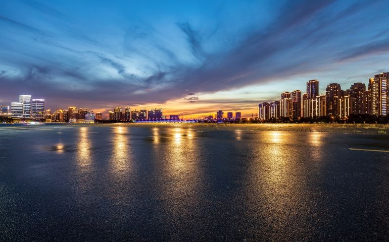 Asphalt road and city skyline with modern building at night in Suzhou, China.