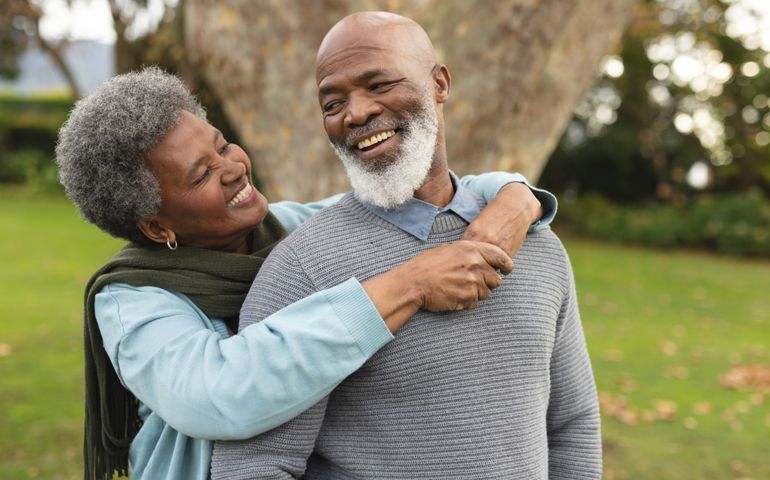 Image of happy african american senior couple posing at camera outdoors in autumn. Family, spending quality time together concept.