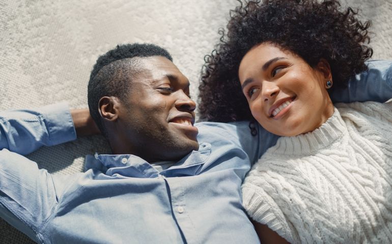 Shot of Cheerful Couple Dreaming and Talking About Future While Hugging on the Living Room Floor. Boyfriend and Girlfriend in Love Spending Quality Time Together At Home. Top View.