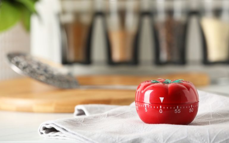Kitchen timer in shape of tomato on white table.