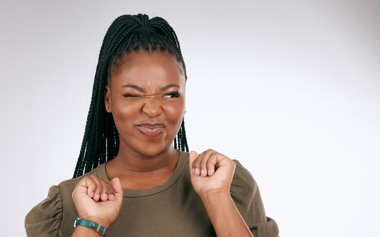 Silly, happy and black woman face with sassy emoji attitude facial expression in studio. White background, isolated and young model with fashion fashion with comic, crazy and goofy gesture alone