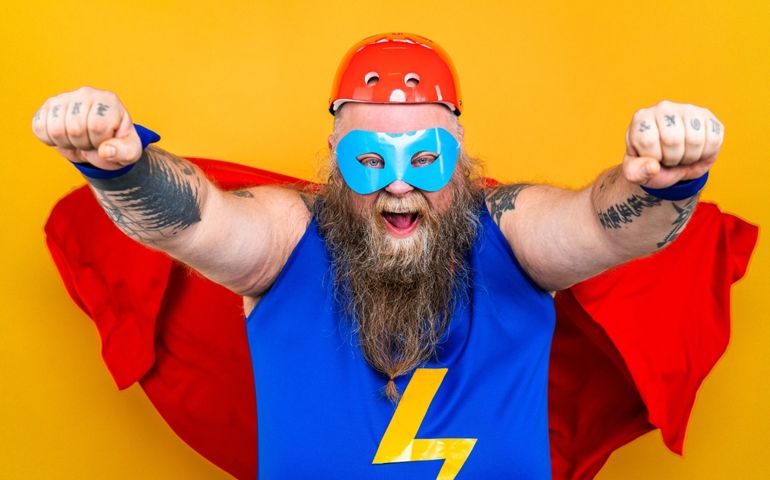 Funny fat man with superhero costume acting as superhuman with superpowers, portrait on colored background