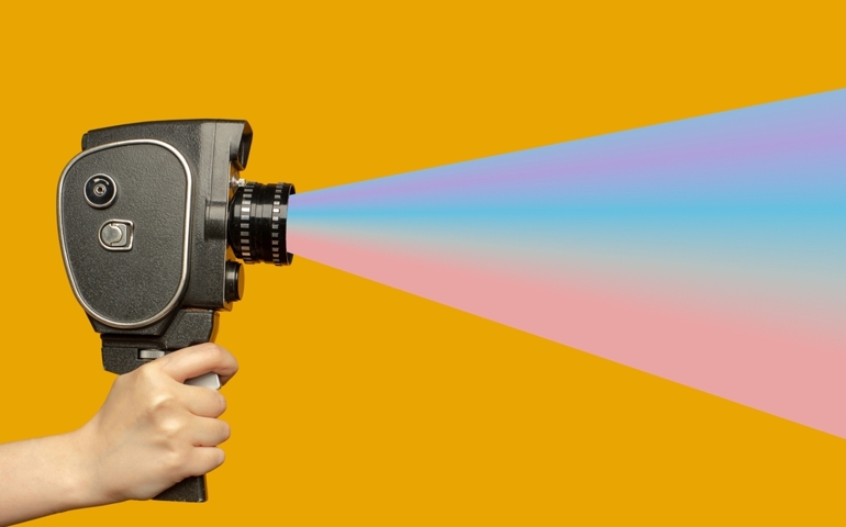 Human hand holding movie camera and spreading fake news