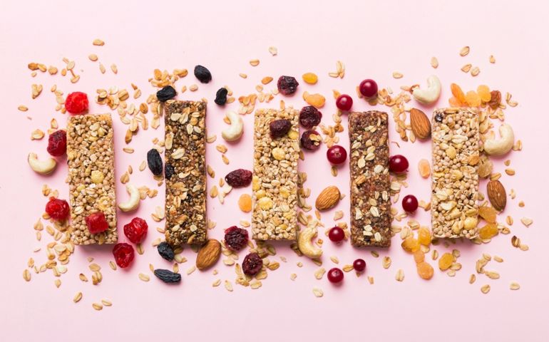 Various granola bars on table background. Cereal granola bars. Superfood breakfast bars with oats, nuts and berries, close up. Superfood concept.