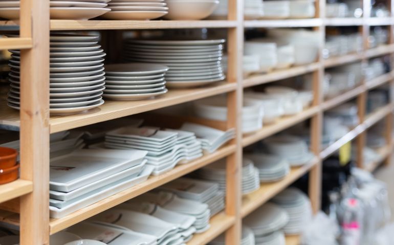 Variety of plates displayed on shelving in household goods store. Kitchen utensils and dishware for sale