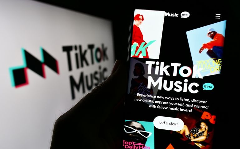 Stuttgart, Germany - 07-30-2023: Person holding cellphone with website of streaming service TikTok Music on screen in front of company logo. Focus on center of phone display. Unmodified photo.