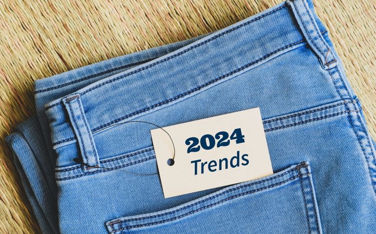 Close up of blue jeans with tag message 2024 trends. Fashion trends for the new year concept. Top view, korai grass mat background.