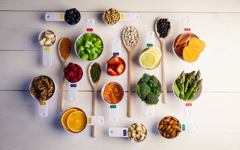 Portion cups and spoons of healthy ingredients on wooden table