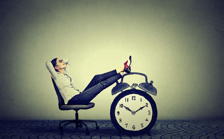 Happy young business woman relaxing sitting in her office. Stress free time management concept