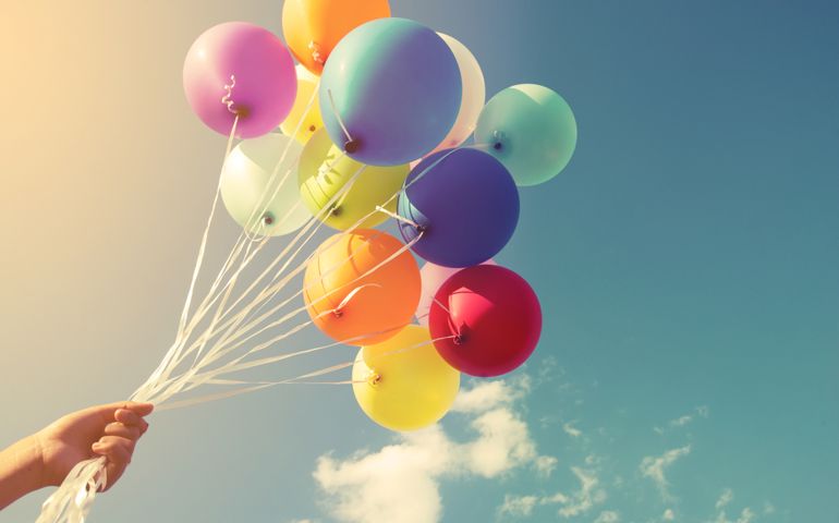 Girl hand holding multicolor balloons done with a retro instagram filter effect, concept of happy birth day in summer and wedding honeymoon party (Vintage color tone)