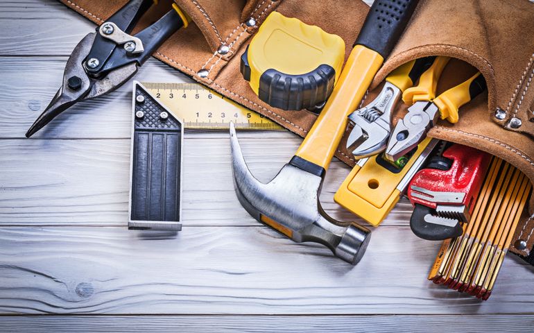 Leather tool belt with construction tooling on wooden board maintenance concept.