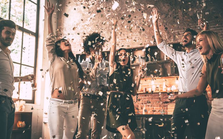 Confetti fun. Group of happy young people throwing confetti and jumping while enjoying home party on the kitchen
