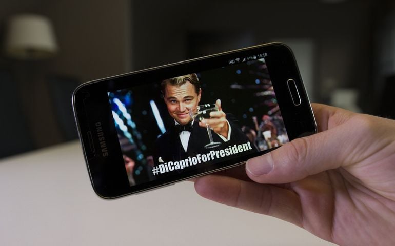 LENDELEDE, BELGIUM - NOVEMBER 28TH 2016: a hand holding a Samsung Galaxy S5 mini mobile phone with the popular DiCaprio For President meme. An illustrative editorial image on an interior background.