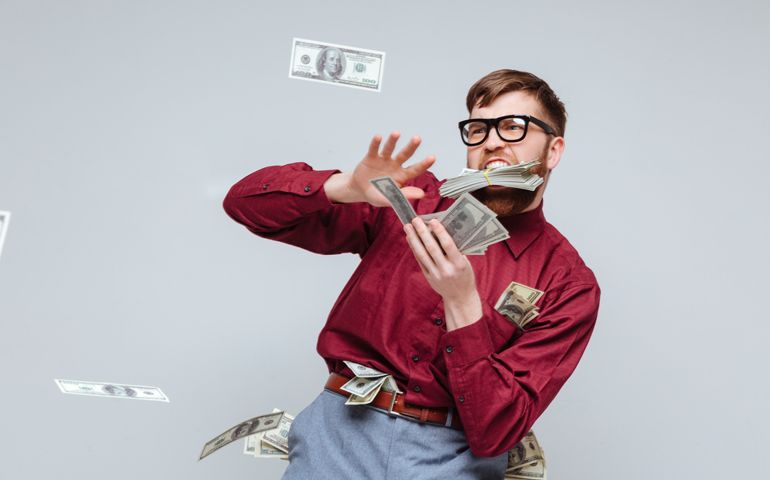 Happy Male playing with money in studio. Isolated gray background