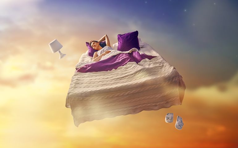 Woman's dreams. Pretty girl is flying in her bed trough star sky.