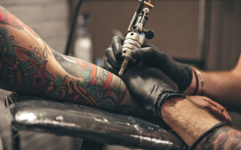 close up tattoo machine. Man creating picture on hand with it in salon