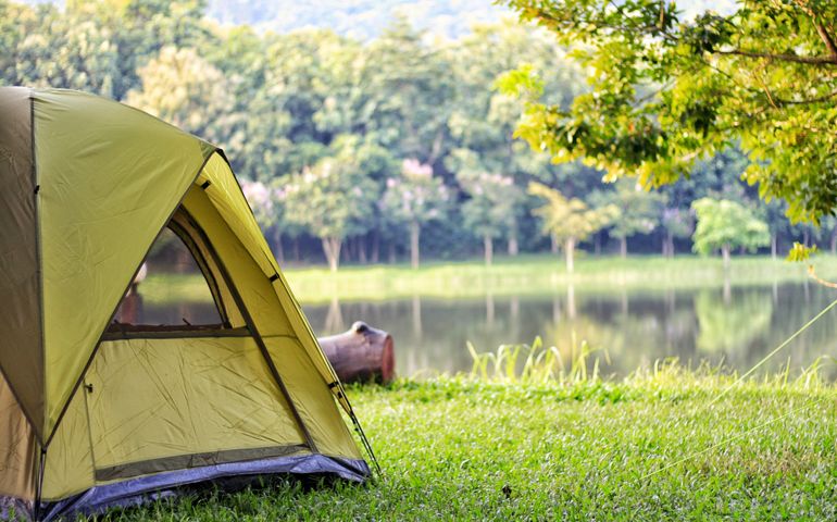 Camping green tent in forest near lake