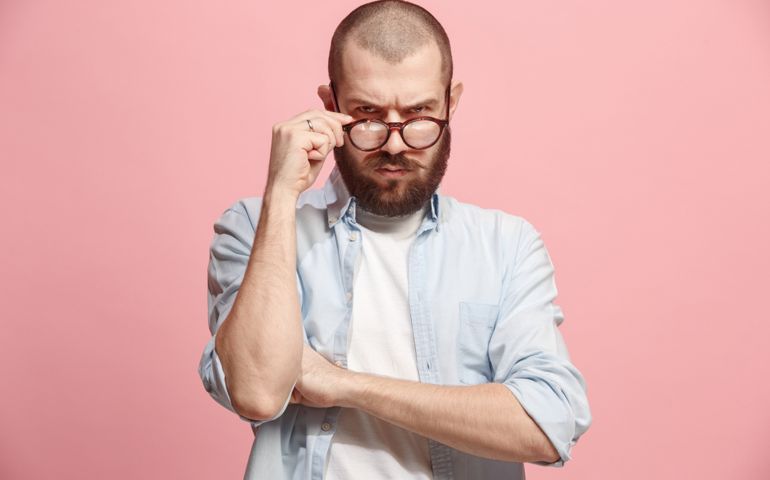 Suspicion. Doubt, mistrust, distrust concept. Doubtful man looking with disbelief expression . Young emotional man. Human emotions, facial expression concept. Studio. Isolated on trendy pink