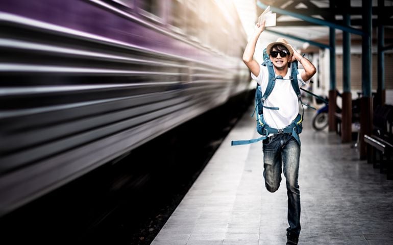 Traveler man running after a moving train from a railway station