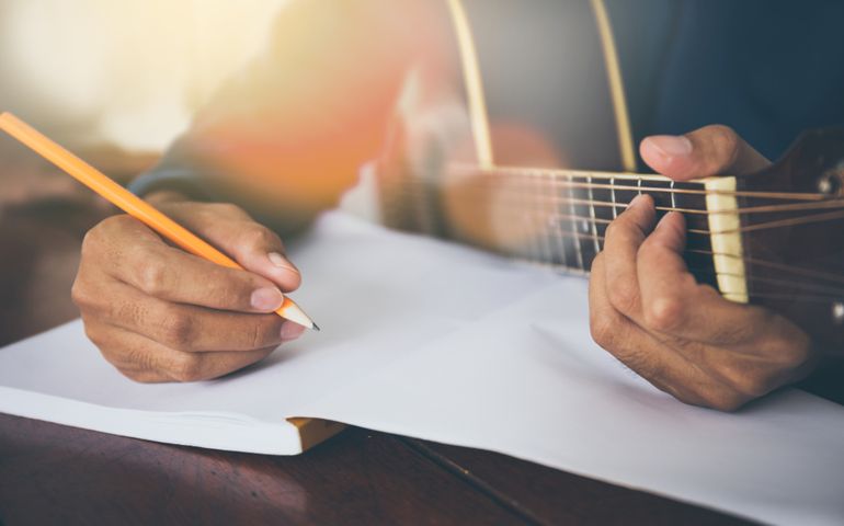songwriter thinking and writing notes,lyrics in book at studio.man playing live acoustic guitar.concept for musician creative.artist composer in work process.people relaxing time with instrument