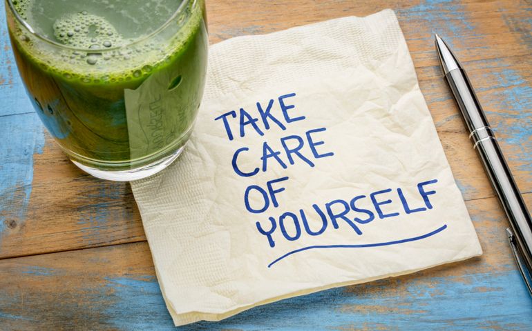 take care of yourself - inspirational handwriting on a napkin with a glass of green juice