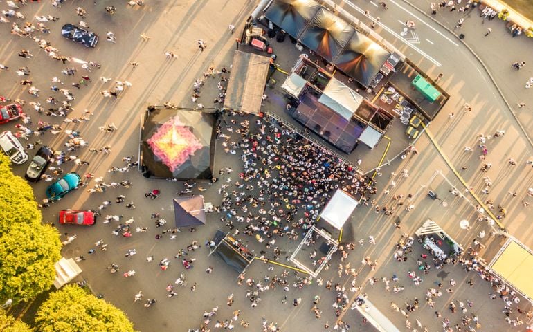 aerial top view of crowd of people standing near the stage on a concert on summer day