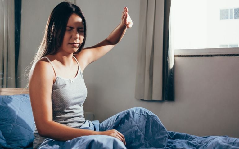 Girl upset waking up with the light bothering her lying on a bed in the morning