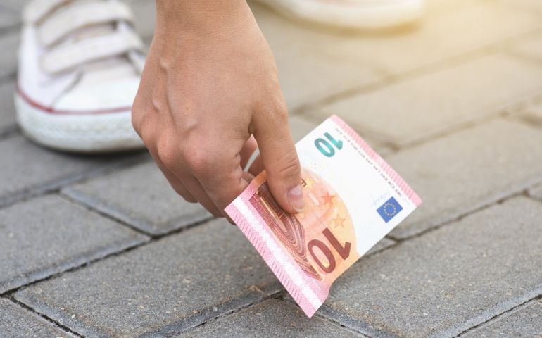 Lost and found money. Woman is picking ten euro banknote from the ground.