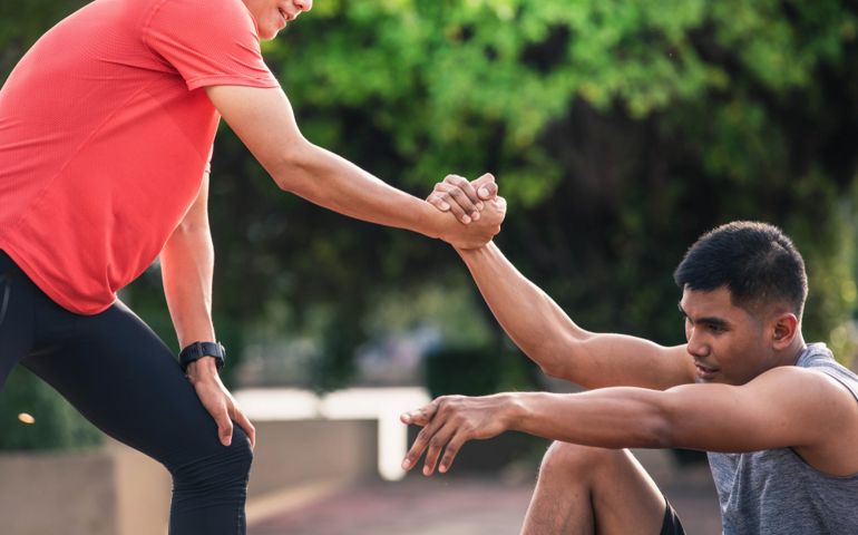 Helping hand outstretched for salvation . Strong hold. Running man helping his friend. Man help each other to run on the running track.