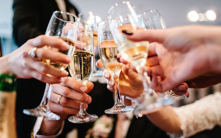 Cheers! People celebrate and raise glasses of wine for toast. Group of man and woman cheering with champagne.