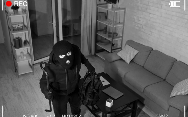 Being Caught. Robber entering house, holding crowbar and looking at CCTV camera, high angle view from above
