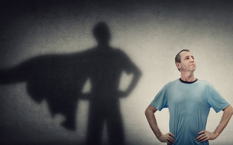 Confident and optimistic middle aged man, hands on hips showing chest, brave gesture, like a powerful superhero casting shadow on the wall. Inner strength, motivation and ambitions, leadership concept