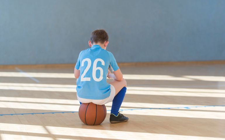 Stressed tired exhausted child with ball in a physical education lesson.