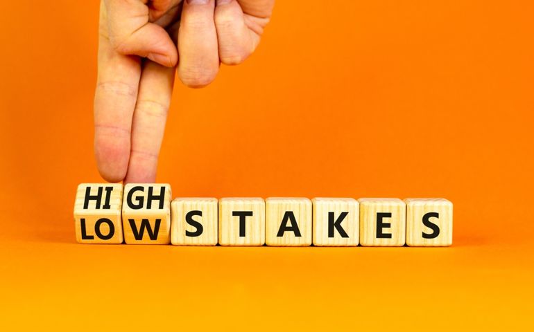 High or low stakes symbol. Concept words High stakes and Low stakes on wooden cubes. Businessman hand.