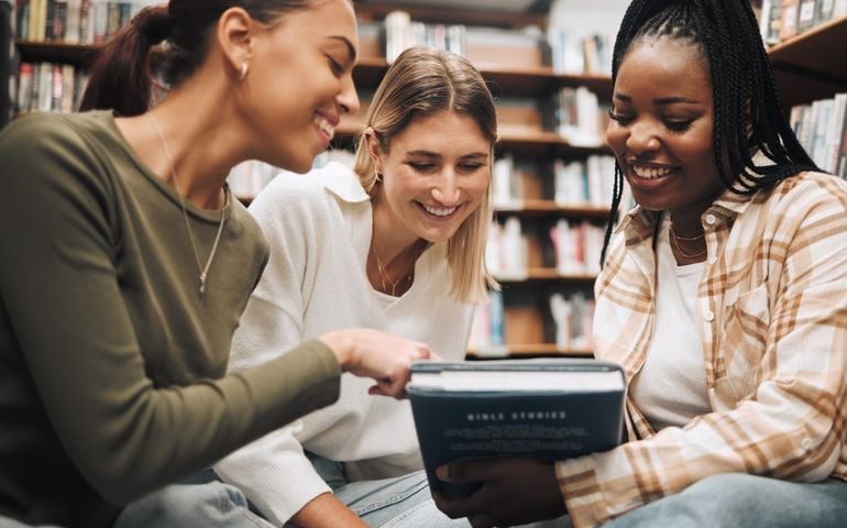 Student, friends and book in school library for education, learning or knowledge together at university. Students smile for book club, books or information for research assignment or group project