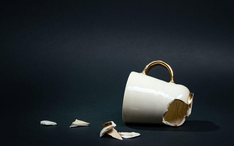 Broken tea cup isolated on black background. Cracked coffee mug and fragile ceramic pieces