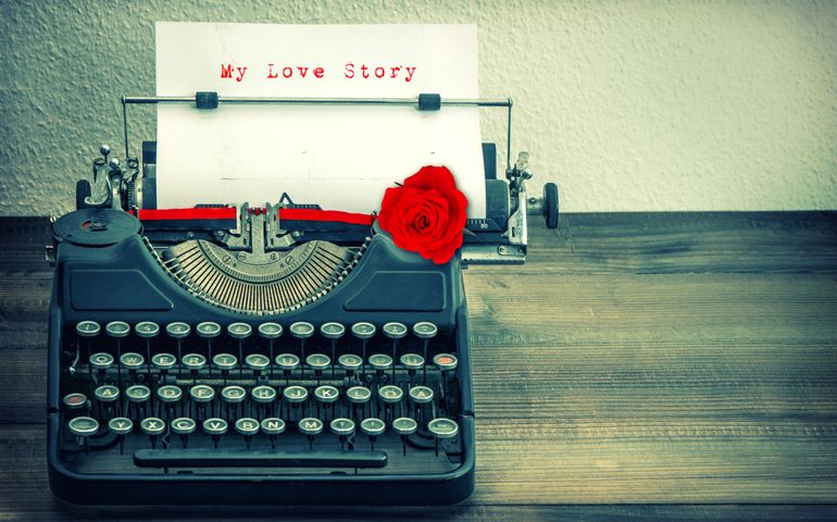 Vintage typewriter with white paper and red rose flower. Sample text My Love Story. Vintage style toned grungy picture