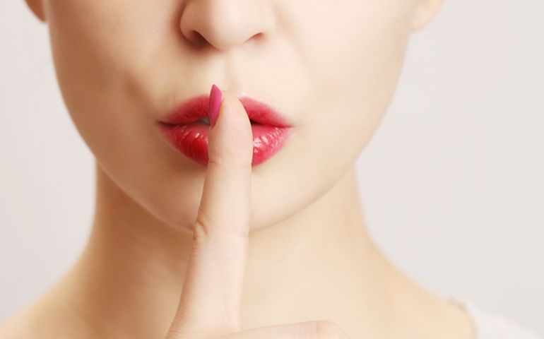 Finger on lips - silent gesture, Woman holding her finger to her lips in a gesture for silence.