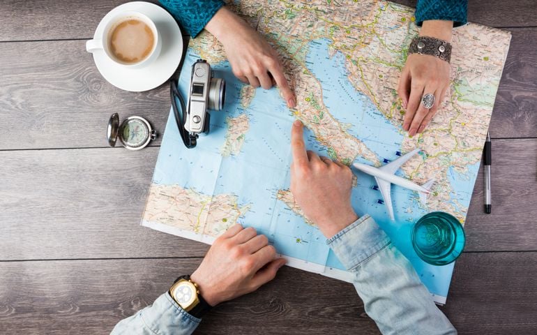 Young couple planning honeymoon vacation trip with map. Top view. Pointing to Europe Rome