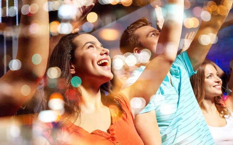 party, holidays, celebration, nightlife and people concept - smiling friends waving hands at concert in club