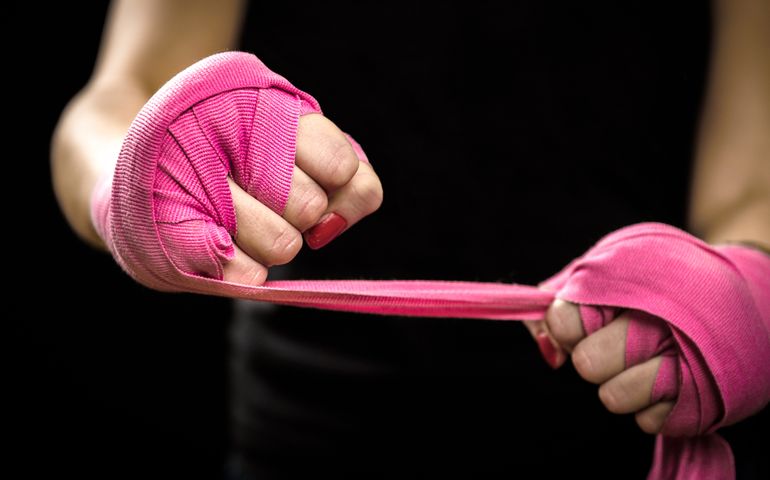 Woman is wrapping hands with pink purple boxing wraps