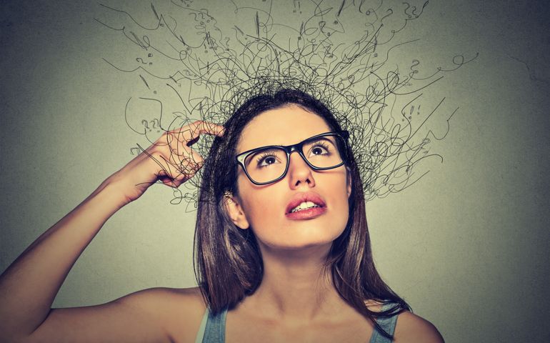 Closeup portrait young woman scratching head, thinking daydreaming with brain melting into lines question marks looking up isolated on gray background. Human facial expressions, emotion