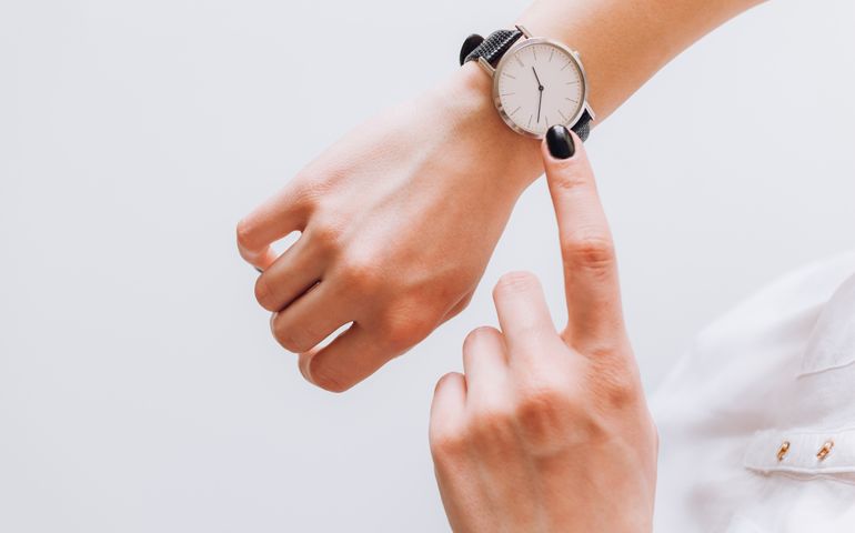 A young business woman is late on time, in a hurry she checks the deadline on her classic watch