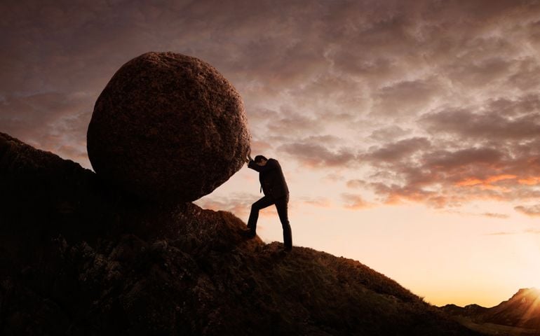 Business concept, Young businessman pushing large stone uphill with copy space