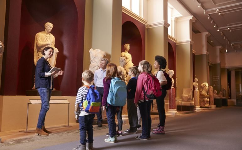 Pupils And Teacher On School Field Trip To Museum With Guide