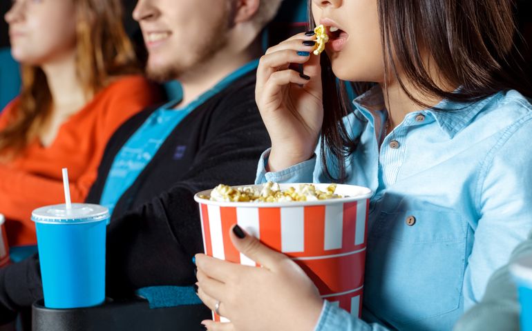Favorite snack. Cropped shot of a woman eating popcorn during movies at the local cinema