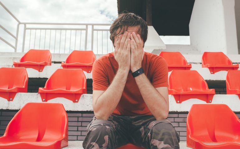 Disappointed man at sport stadium watching the game in disbelief while his team is losing the match