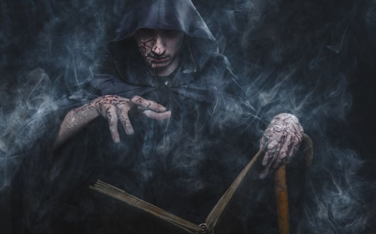 Necromancy sorcerer casting black magic spell using his book of shadows