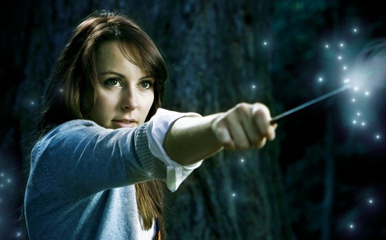 Teenage wizard girl with magic wand casting spells in a enchanted fantasy forest